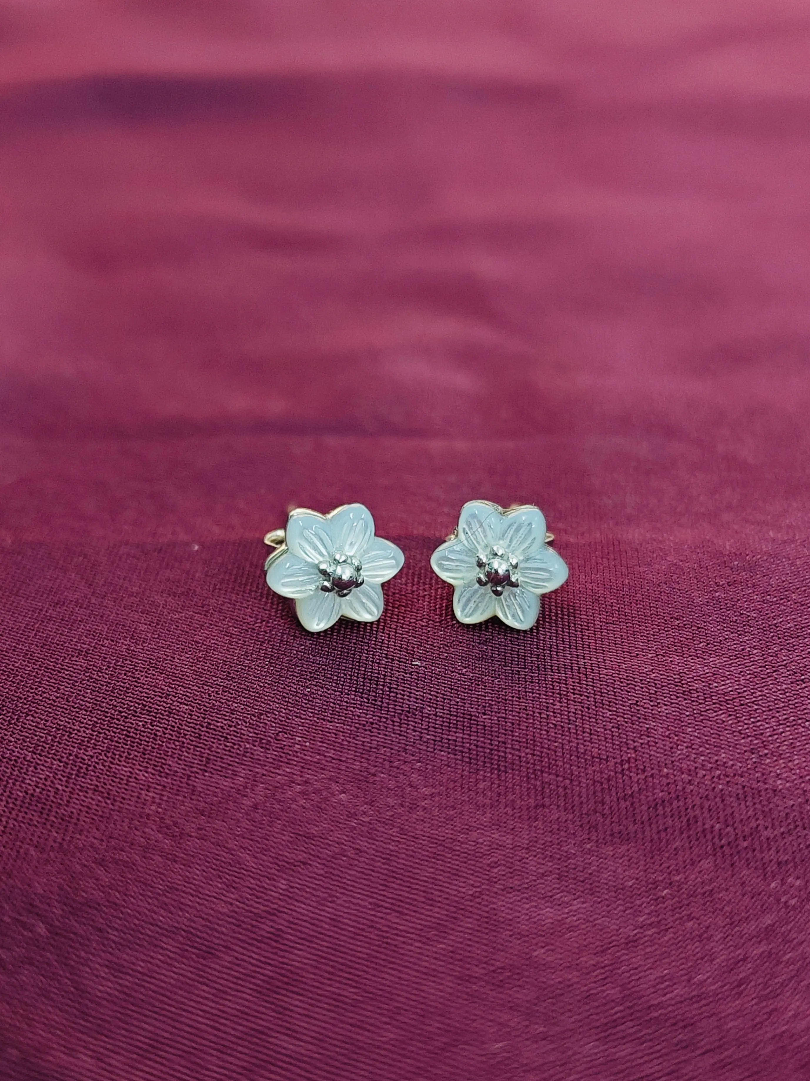 Flower-shaped earrings on a purple fabric background